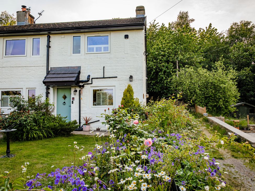 A house with a garden filled with flowers at Wells Cottage in Holmfirth