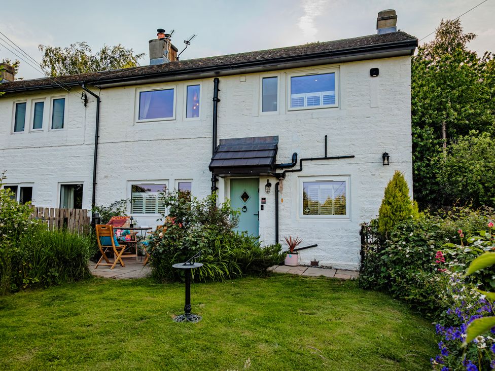 A house with garden and patio seating area at Wells Cottage in Holmfirth