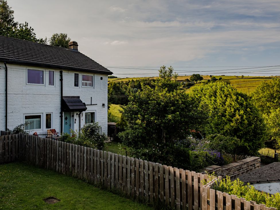 A house with a garden and trees at Wells Cottage in Holmfirth