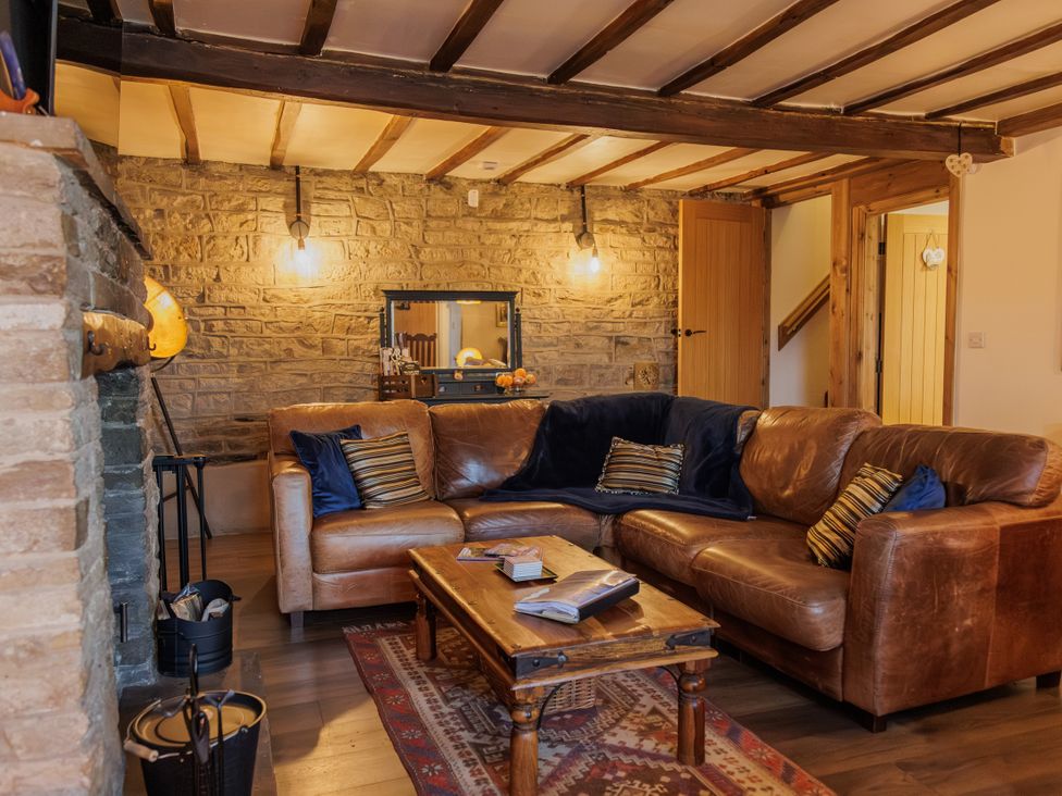 A living room with a leather sofa and coffee table at Wells Cottage in Holmfirth