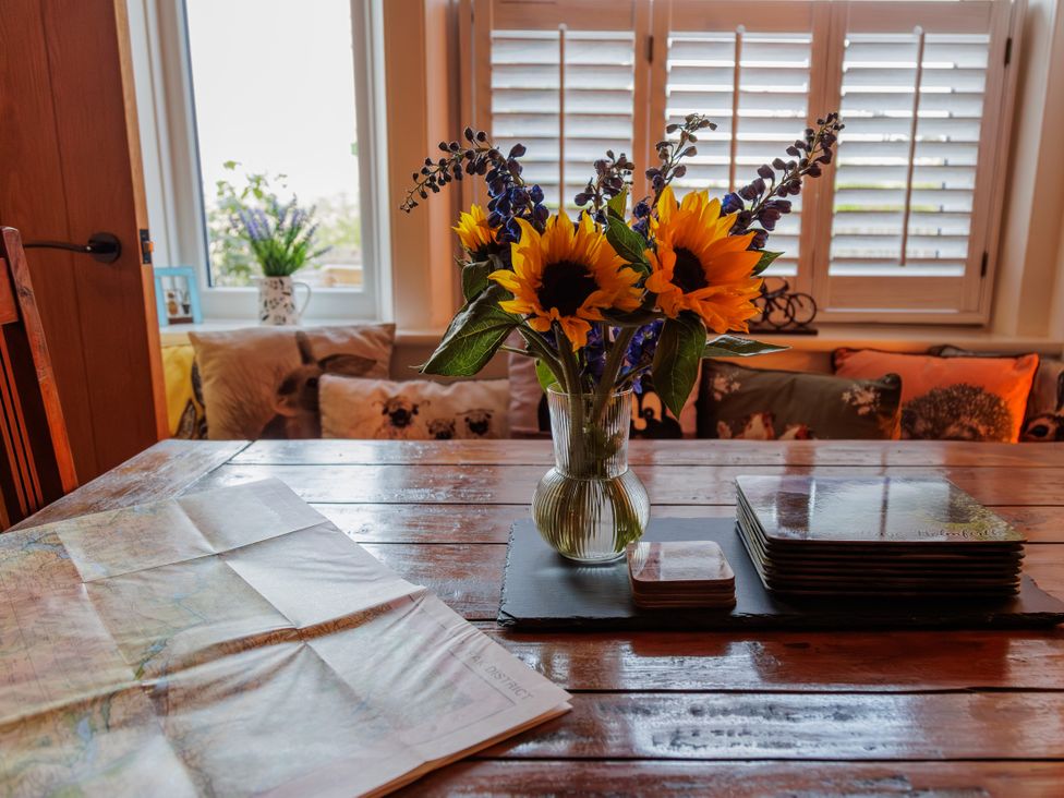 A dining room with a table, flowers, and a map at Wells Cottage in Holmfirth