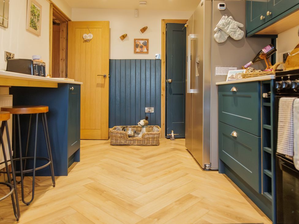 A kitchen with cabinets and a refrigerator at Wells Cottage in Holmfirth