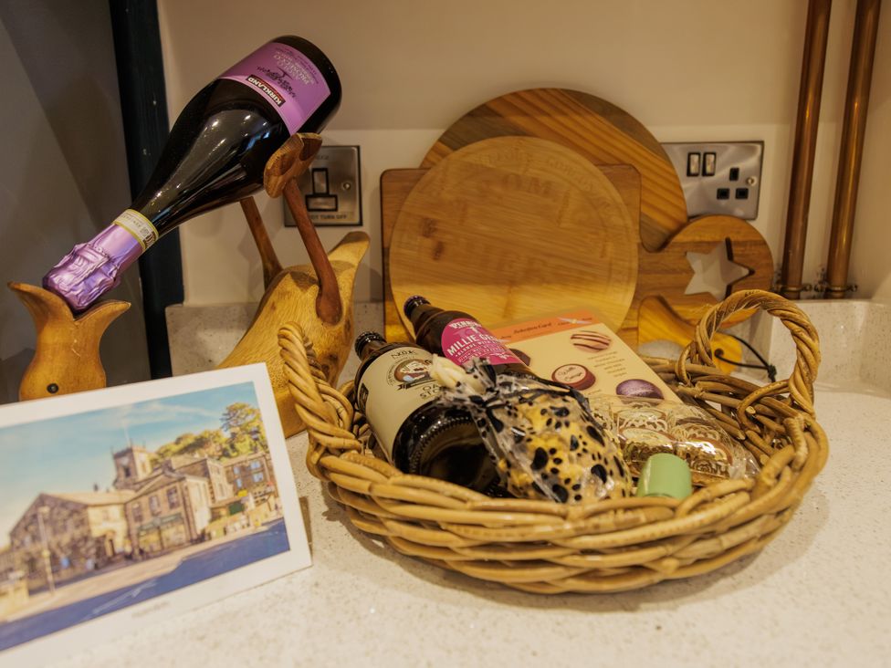 A kitchen counter with a basket of drinks and a card at Wells Cottage in Holmfirth