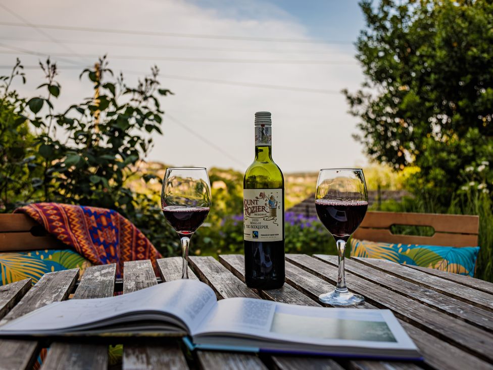 A table with wine glasses and a book at Wells Cottage in Holmfirth