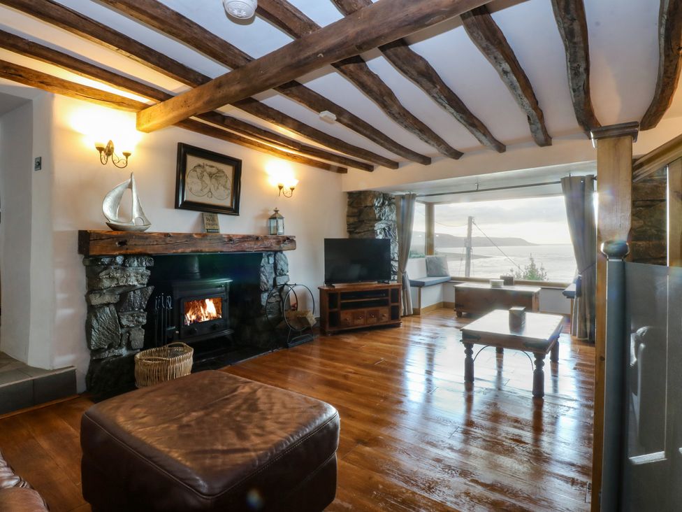 A living room with a fireplace and television at Ty'n-Y-Ffynnon Cottage Barmouth