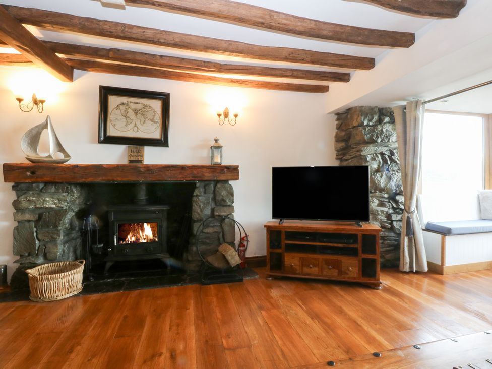 A living room with a fireplace and television at Ty'n-Y-Ffynnon Cottage in Barmouth