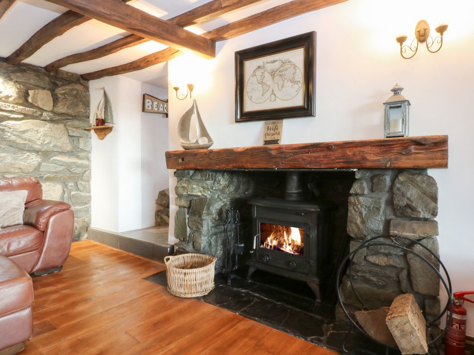 A living room featuring a fireplace and a stone wall at Ty'n-Y-Ffynnon Cottage in Barmouth