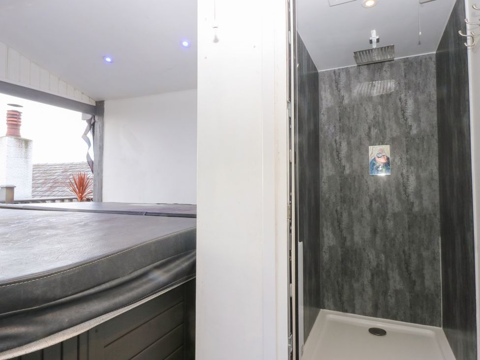 A bathroom with a hot tub and a shower at Ty'n-Y-Ffynnon Cottage in Barmouth