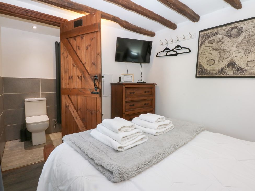 A bedroom with a bed and towels at Ty'n-Y-Ffynnon Cottage Barmouth