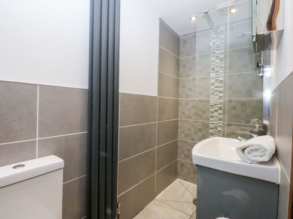 A bathroom with a toilet, shower, and sink at Ty'n-Y-Ffynnon Cottage Barmouth