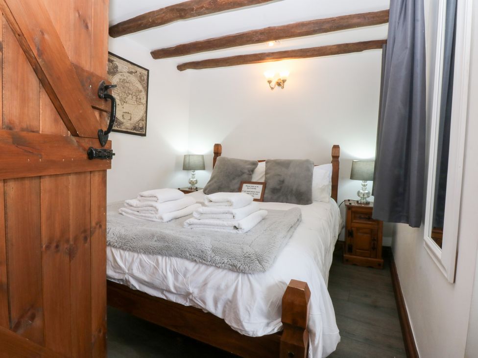 A bedroom with a bed and towels at Ty'n-Y-Ffynnon Cottage in Barmouth