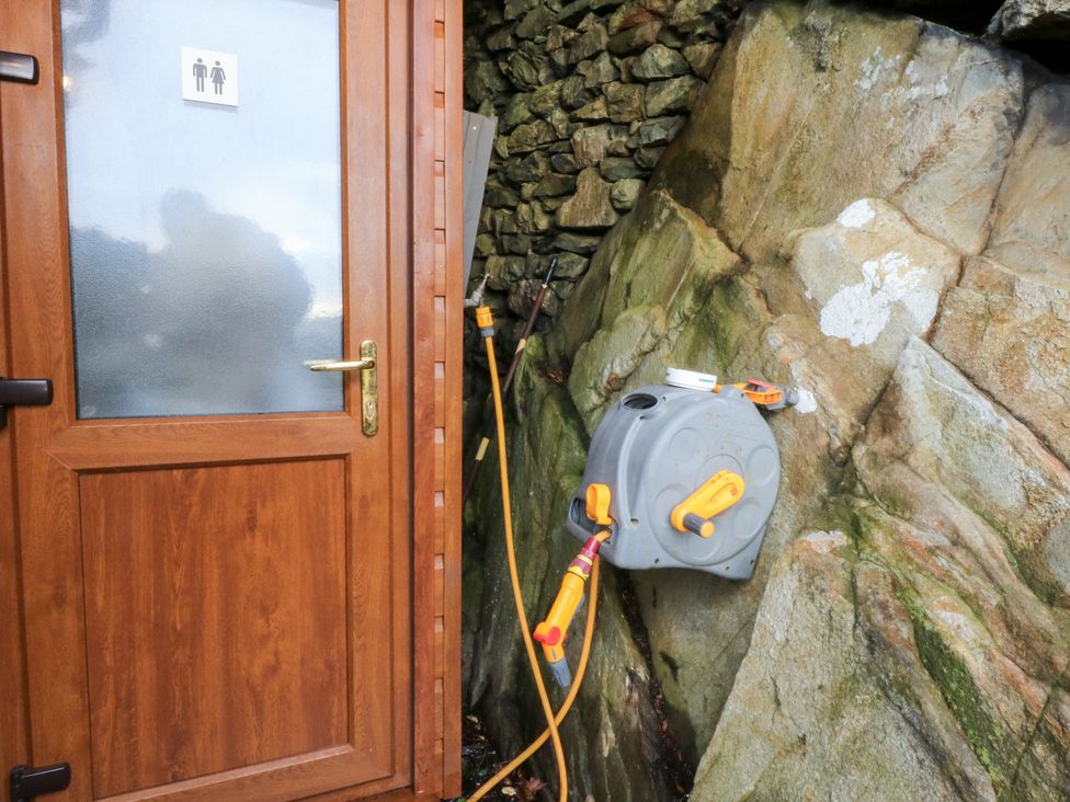 An outdoor bathroom door with a sign and water hose reel at Ty'n-Y-Ffynnon Cottage Barmouth