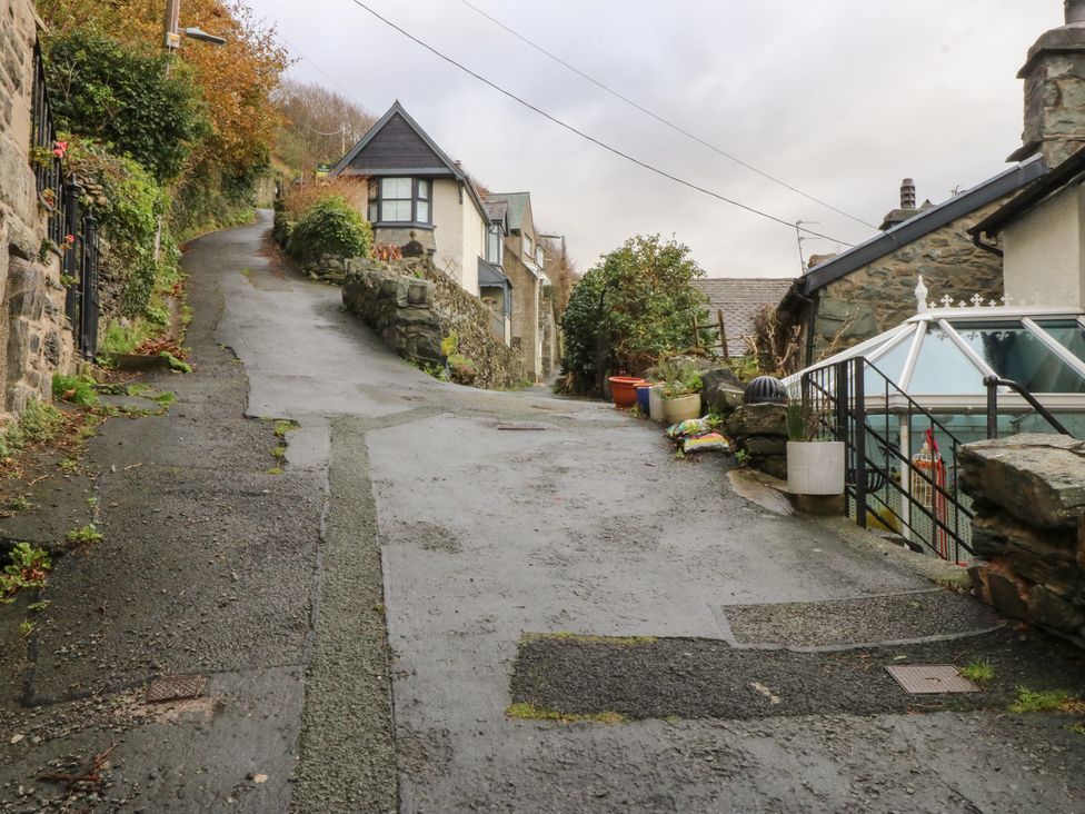 An outdoor view of a sloped road with houses and plants at Ty'n-Y-Ffynnon Cottage in Barmouth