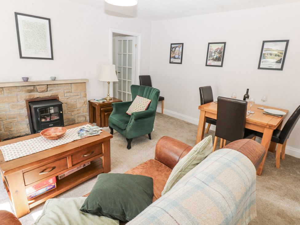 A living room with a fireplace and dining area at Joyces Cottage, 2 Brown Hill Low Row near Reeth