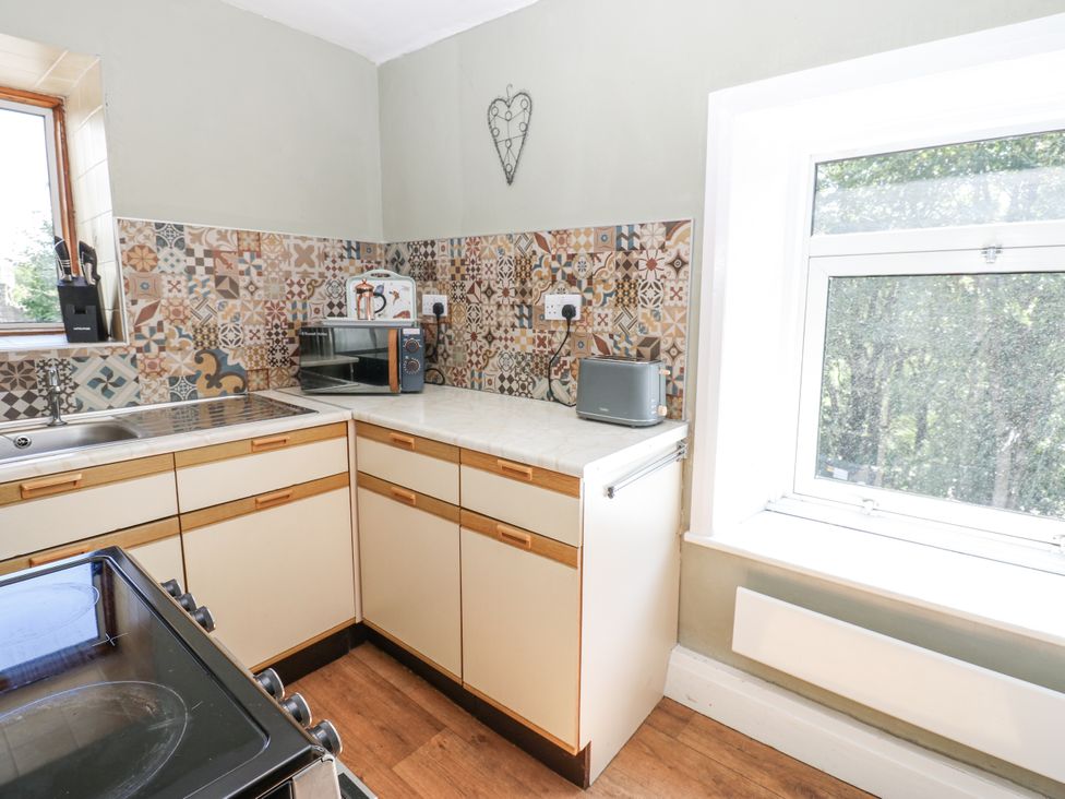 A kitchen with a sink, oven, microwave, and window at Joyces Cottage, 2 Brown Hill Low Row near Reeth