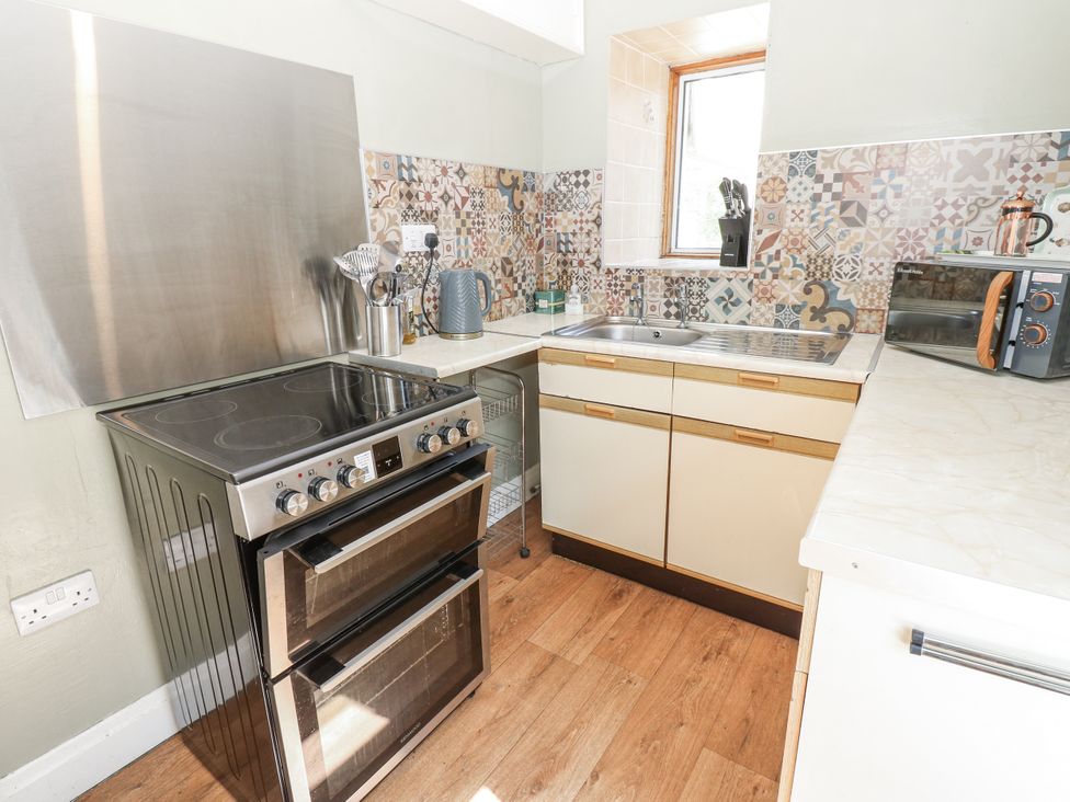 A kitchen with stove, oven, sink, and microwave at Joyces Cottage, 2 Brown Hill, Low Row near Reeth