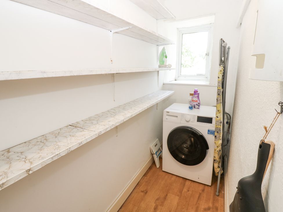 A laundry room with shelves and a washing machine at Joyces Cottage, 2 Brown Hill Low Row near Reeth