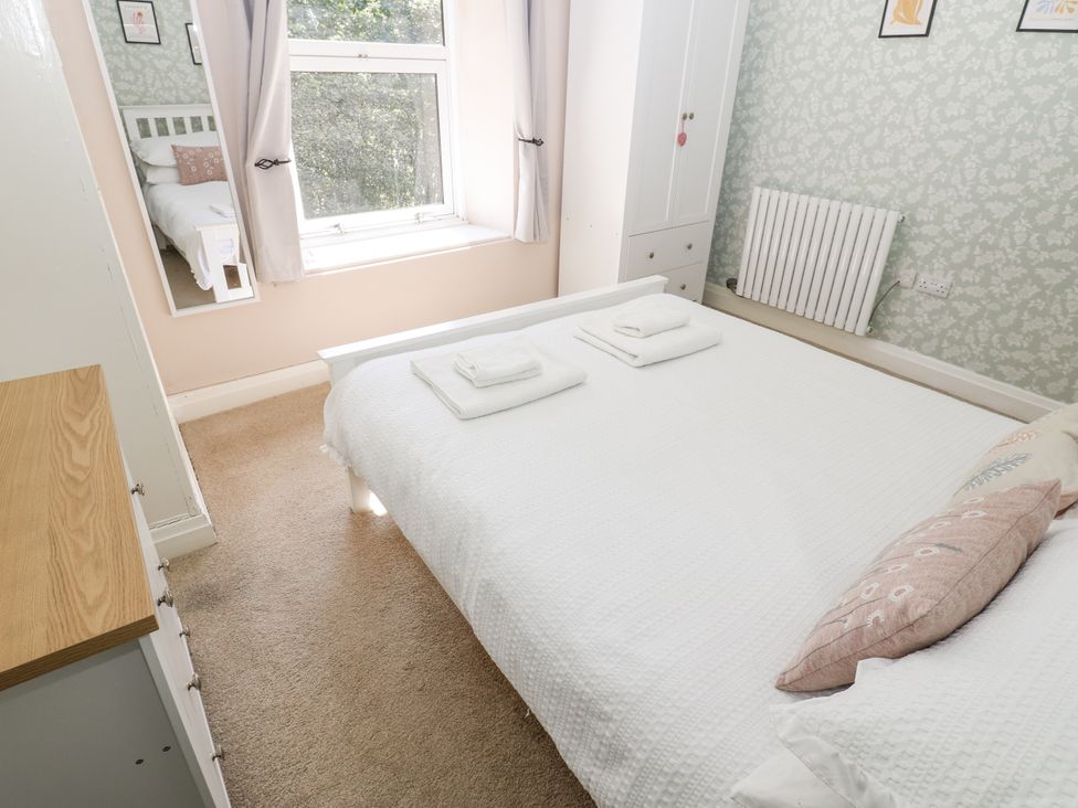 A bedroom with a bed, wardrobe and window at Joyces Cottage, 2 Brown Hill Low Row near Reeth