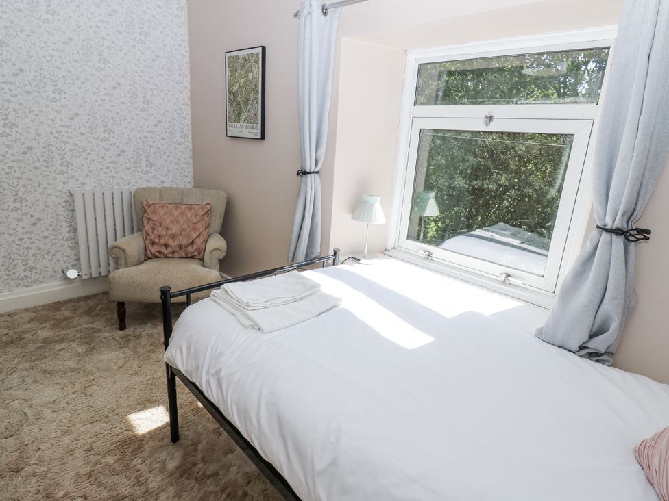 A bedroom with a bed, chair, and window at Joyces Cottage, 2 Brown Hill Low Row near Reeth