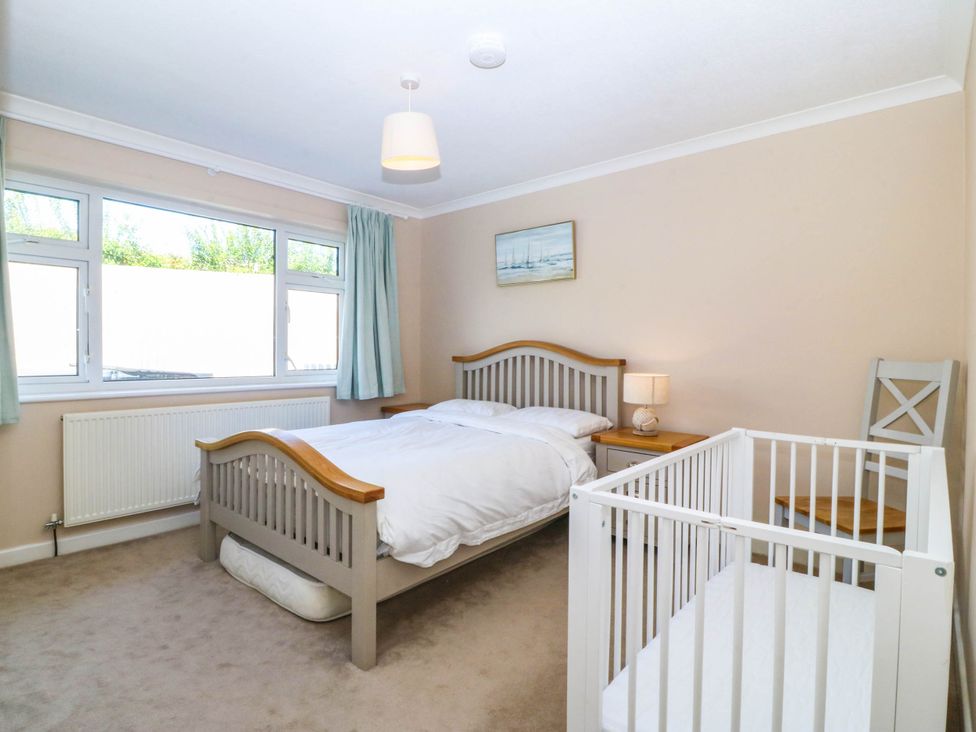 A bedroom with a bed and a crib at 7 Maes Awel in Abersoch