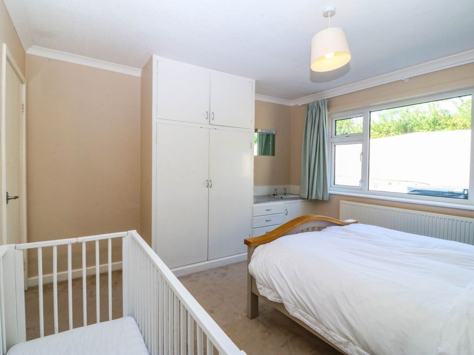 A bedroom with a bed and a crib at 7 Maes Awel Abersoch