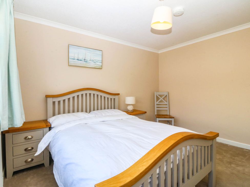 A bedroom with a bed and nightstand at 7 Maes Awel in Abersoch