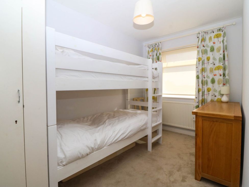 A bedroom with a bunk bed and a nightstand at 7 Maes Awel Abersoch