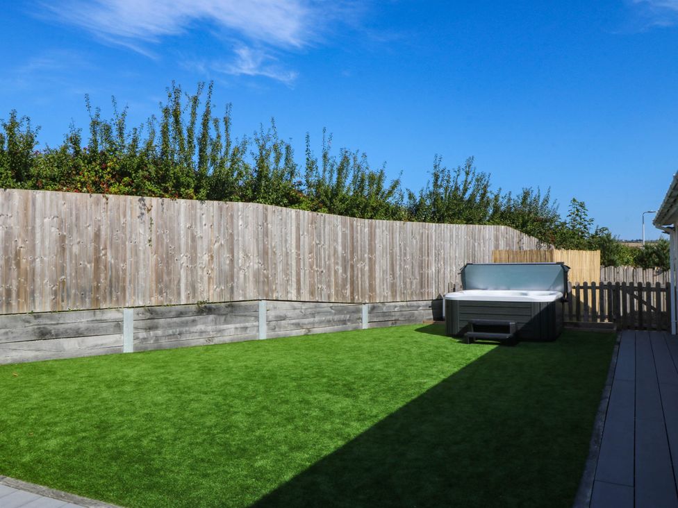 A garden with a hot tub and grass at 7 Maes Awel in Abersoch
