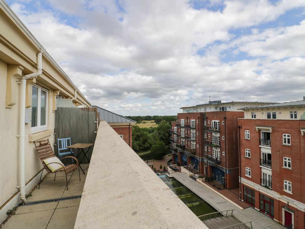 A balcony with chairs and a table overlooking a building and a field at 63 Vista Heights in Solihull