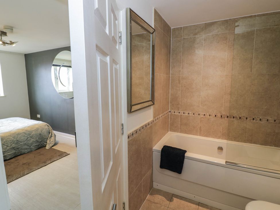 A bathroom with a bathtub and mirror at 63 Vista Heights in Solihull