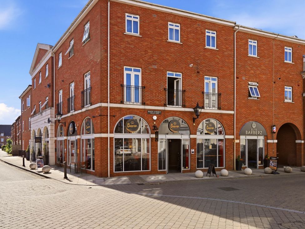 An outdoor view of a brick building with shops on a street at 63 Vista Heights in Solihull