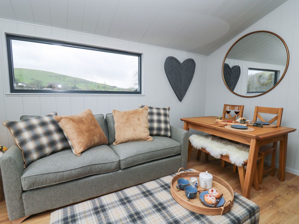 A living room with a sofa and dining table at Fawn’s Rest in Nantmel near Rhayader