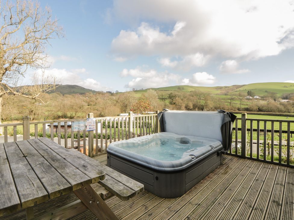 An outdoor area with a hot tub and wooden table at Fawn’s Rest Nantmel near Rhayader