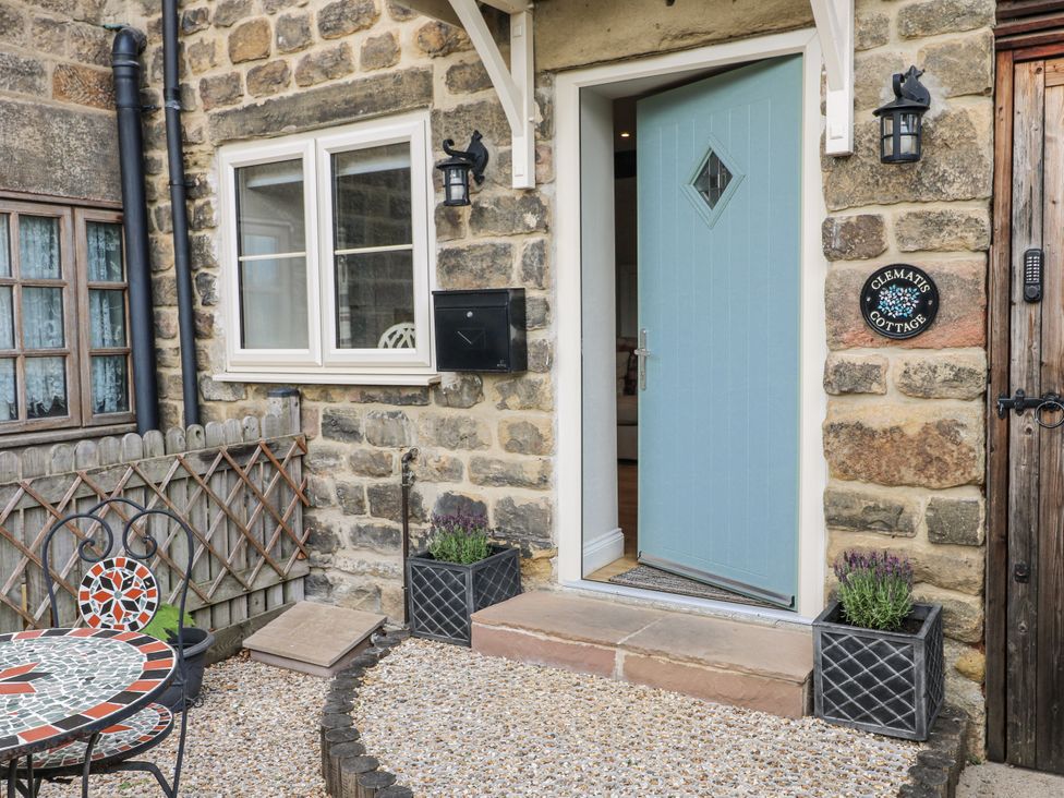 An outdoor entrance with a blue door and seating at Clematis Cottage in Fritchley near Crich
