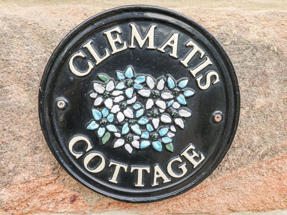A plaque with the text Clematis Cottage and floral design at Clematis Cottage in Fritchley near Crich
