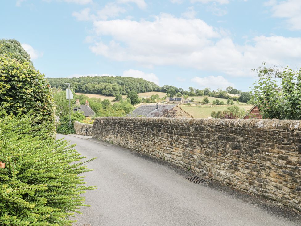 A view of a stone wall and houses along a road at Clematis Cottage in Fritchley near Crich