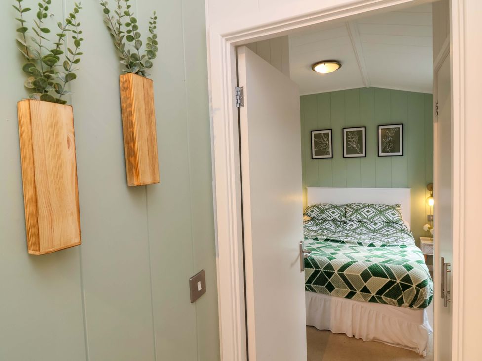 A bedroom with a bed and wall art at Daffodil Lodge in Mullacott near Ilfracombe