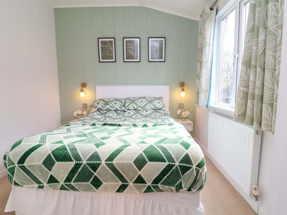 A bedroom with a bed and nightstand at Daffodil Lodge in Mullacott near Ilfracombe