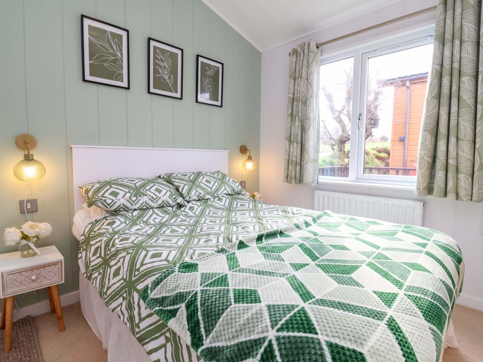 A bedroom with a bed and bedside table at Daffodil Lodge Mullacott near Ilfracombe