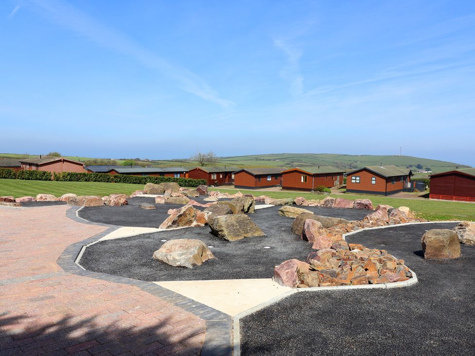An outdoor area with lodges and rocks at Daffodil Lodge in Mullacott near Ilfracombe