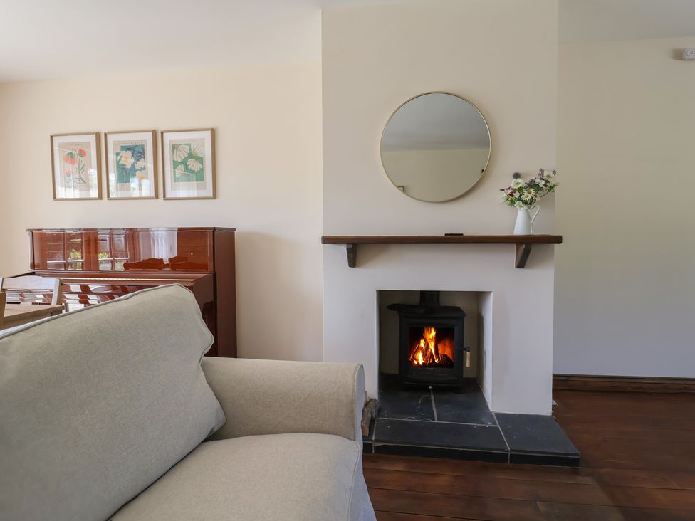 A living room with a piano and fireplace at 10 The Gardens Rousdon near Lyme Regis