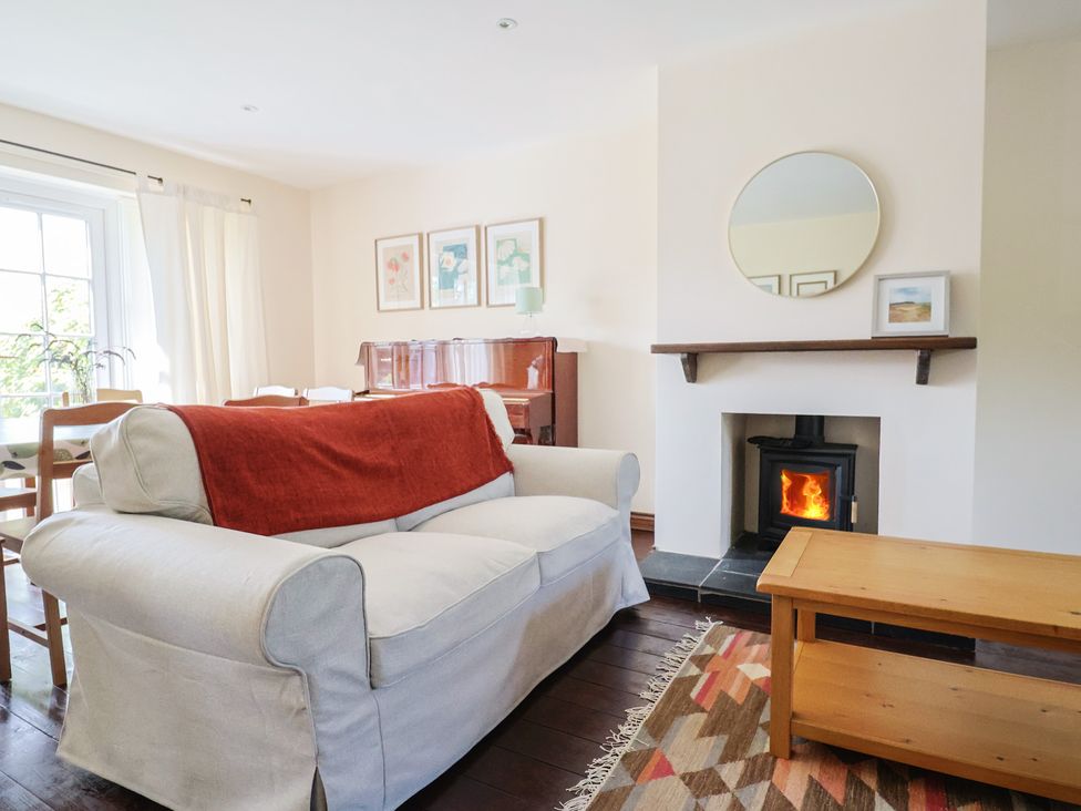 A living room with a sofa and piano at 10 The Gardens Rousdon near Lyme Regis