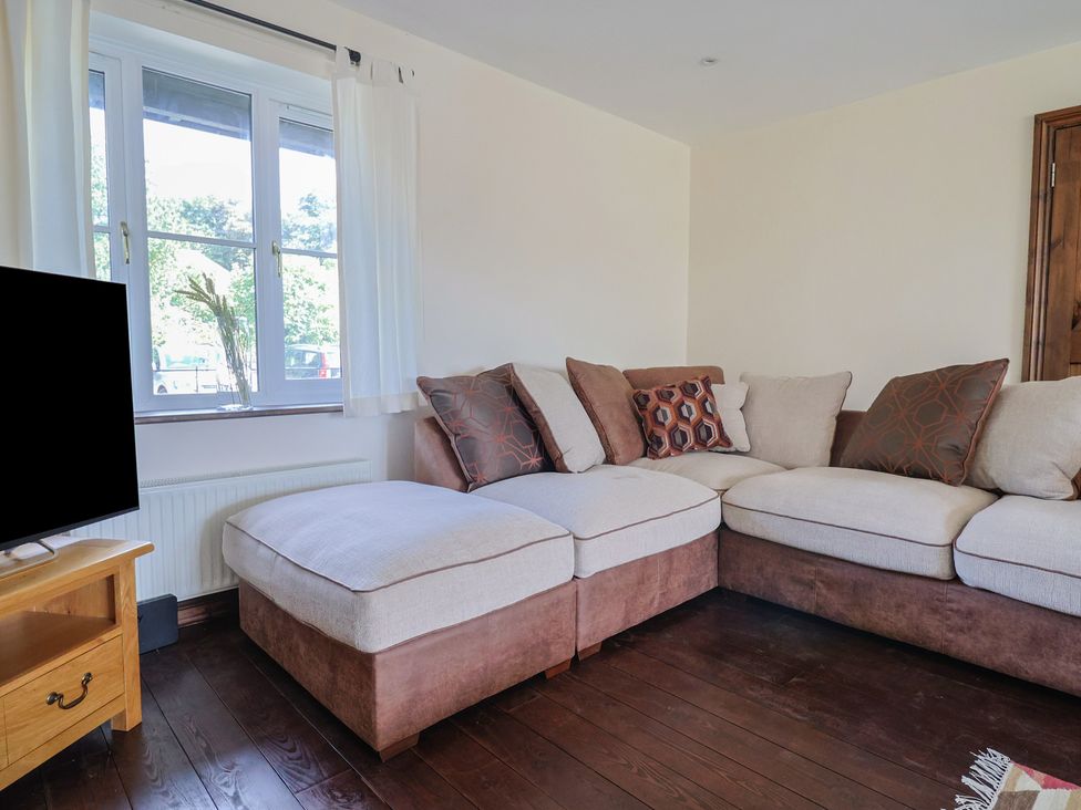 A sofa with cushions and a television in a living room at 10 The Gardens Rousdon near Lyme Regis