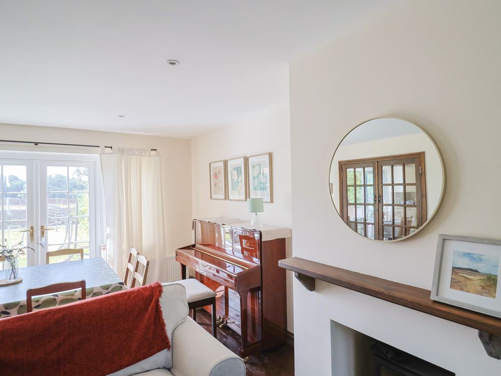 A living room with a piano and dining table at 10 The Gardens Rousdon near Lyme Regis