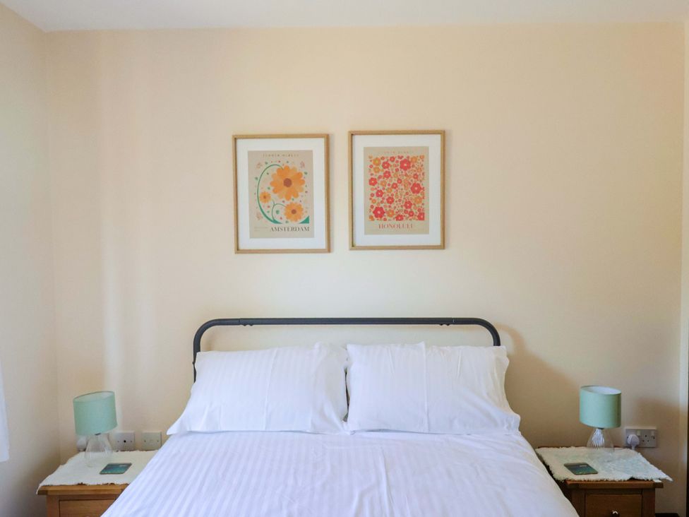 A bedroom with a bed and framed art at 10 The Gardens Rousdon near Lyme Regis
