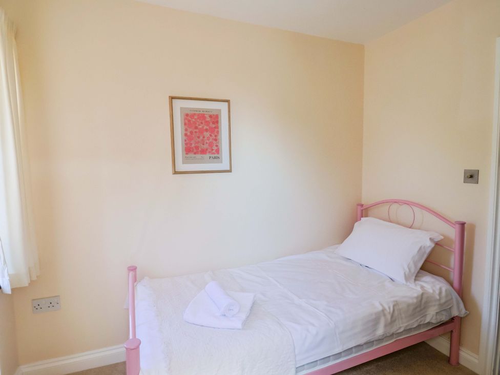 A bedroom with a pink bed and wall art at 10 The Gardens in Rousdon near Lyme Regis