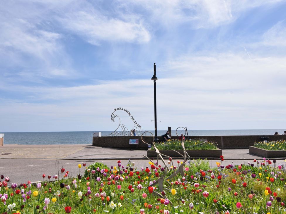 A seaside view with flowers and a sculpture at 10 The Gardens Rousdon near Lyme Regis