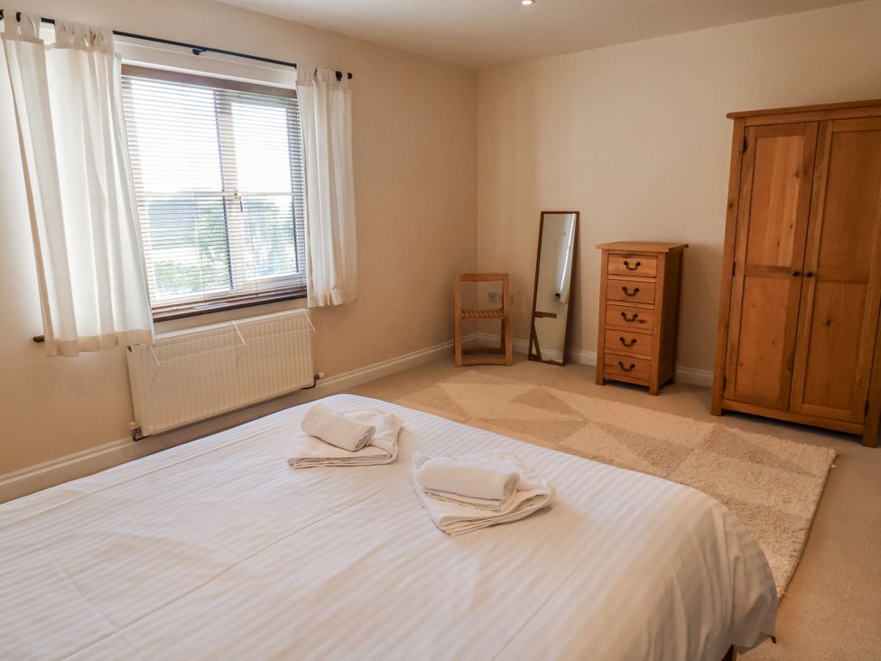 A bedroom with a bed, chair, mirror, dresser, and wardrobe at 10 The Gardens Rousdon near Lyme Regis