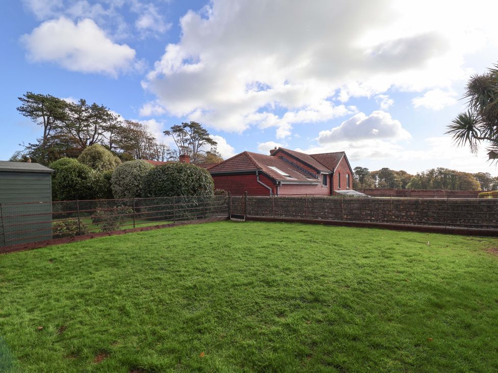 A garden with grass, a shed, and trees at 10 The Gardens Rousdon near Lyme Regis