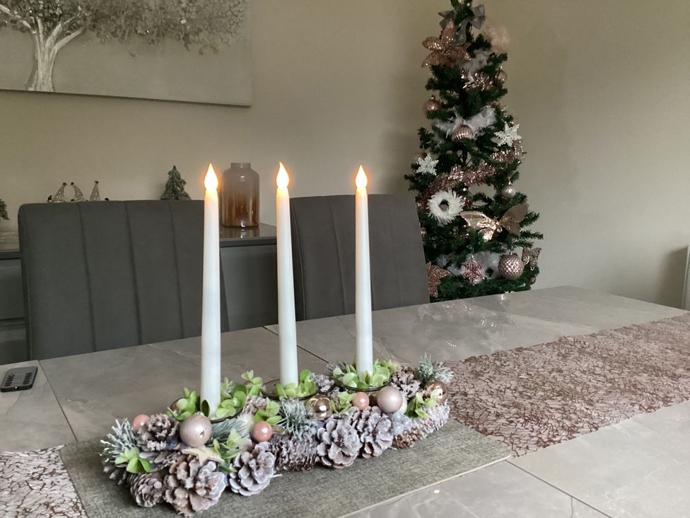 A dining table with candles and pine cones at Seapoint in Primrose Valley